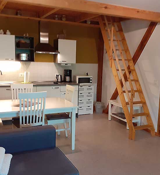 Wohnbereich mit Küche und Holztreppe in der Ferienwohnung Strohboden